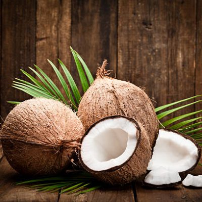 Two whole coconuts, an open coconut and coconut pieces shot on rustic wood table. DSRL studio photo taken with Canon EOS 5D Mk II and Canon EF 100mm f/2.8L Macro IS USM