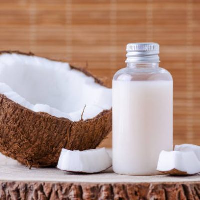 cosmetic bottle and fresh organic coconut for skincare, natural brown background